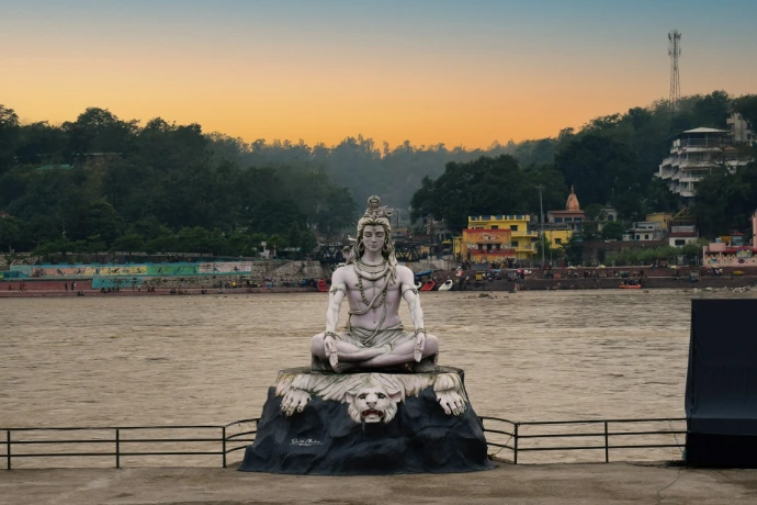 a statue sitting on top of a rock near a body of water